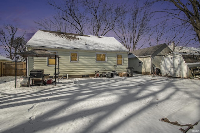 snow covered back of property with a shed