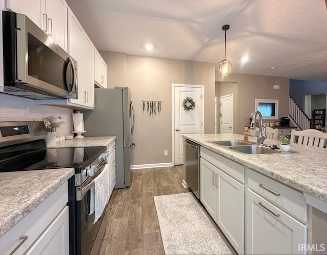 kitchen with appliances with stainless steel finishes, decorative light fixtures, sink, and white cabinets