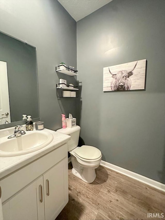 bathroom with wood-type flooring, toilet, a textured ceiling, and vanity