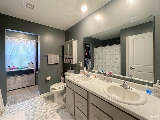 bathroom with vanity, toilet, and a textured ceiling