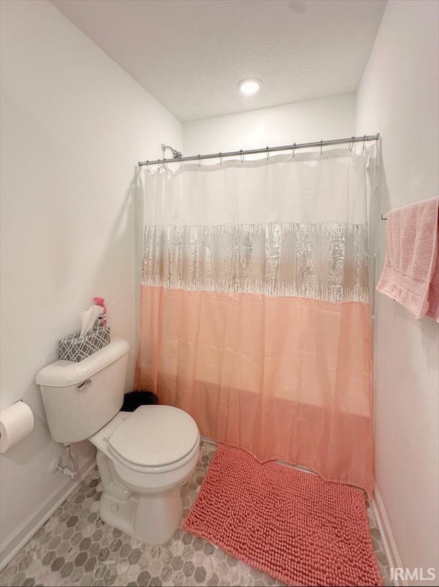 bathroom featuring toilet and curtained shower