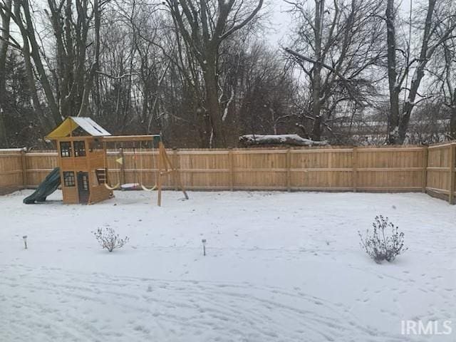 yard layered in snow featuring a playground