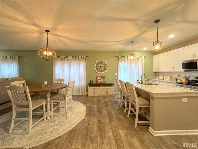 kitchen featuring sink, stainless steel appliances, white cabinets, dark hardwood / wood-style flooring, and decorative light fixtures