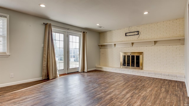 unfurnished living room featuring a fireplace, dark hardwood / wood-style floors, and brick wall