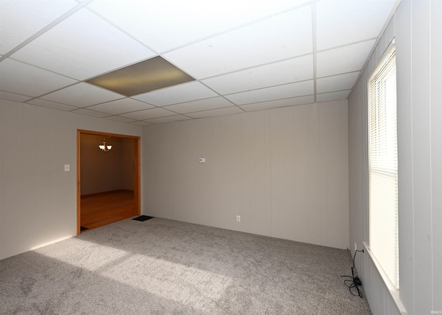 carpeted spare room featuring a drop ceiling