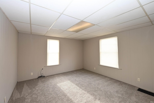 carpeted spare room with a drop ceiling