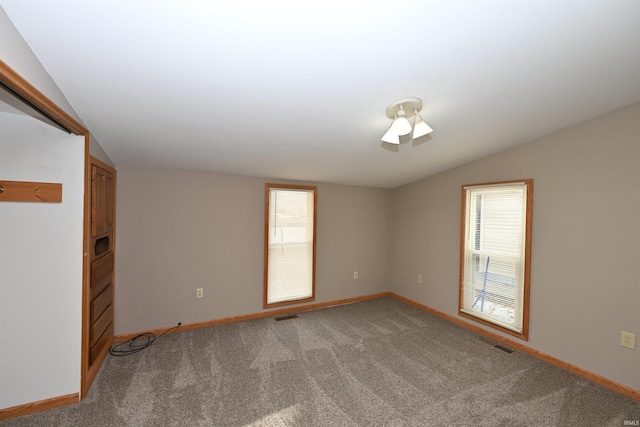 carpeted empty room with plenty of natural light and vaulted ceiling