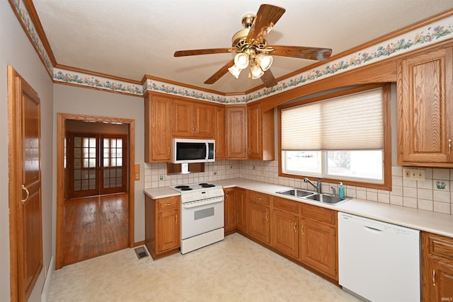 kitchen featuring white appliances, sink, backsplash, ornamental molding, and ceiling fan