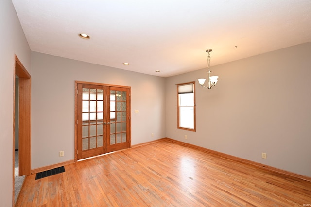 empty room with plenty of natural light, light hardwood / wood-style flooring, and french doors