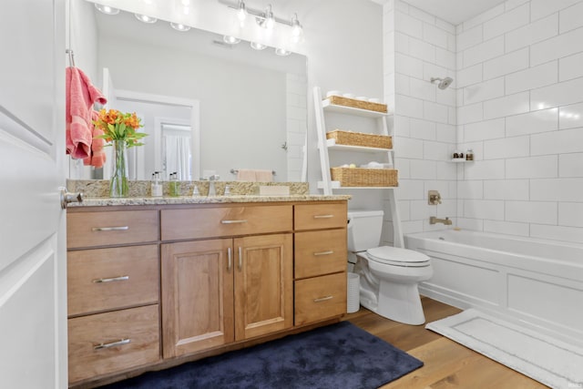 full bathroom with vanity, hardwood / wood-style flooring, toilet, and tiled shower / bath combo