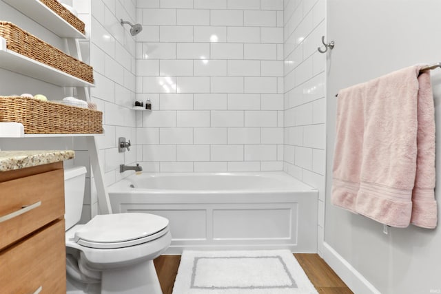 full bathroom featuring wood-type flooring, toilet, tiled shower / bath, and vanity