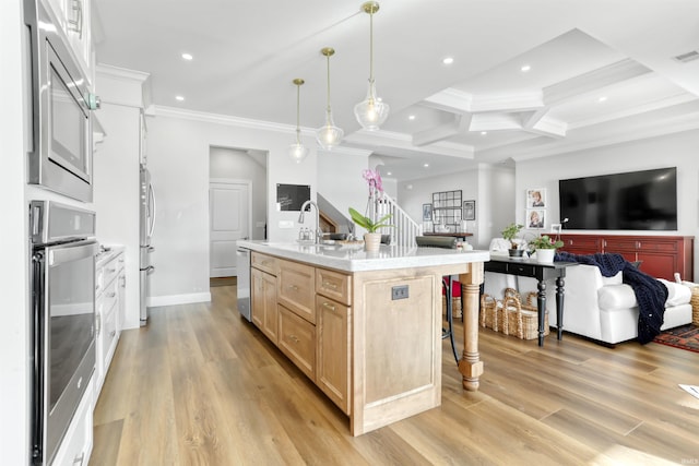 kitchen with appliances with stainless steel finishes, coffered ceiling, a breakfast bar, a center island with sink, and light brown cabinets