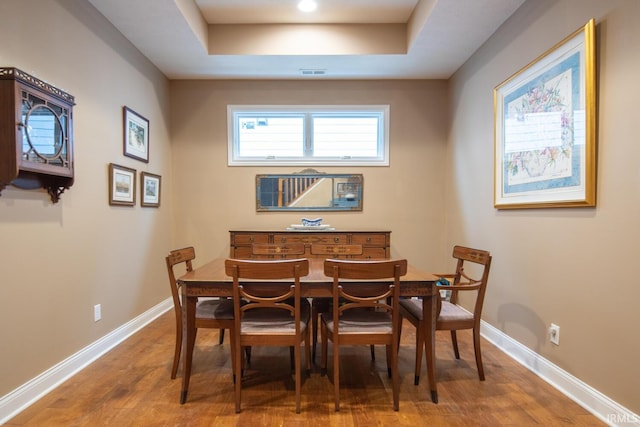 dining space with hardwood / wood-style flooring and a raised ceiling