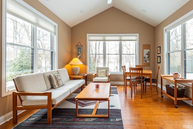 living room featuring plenty of natural light, lofted ceiling, and light wood-type flooring