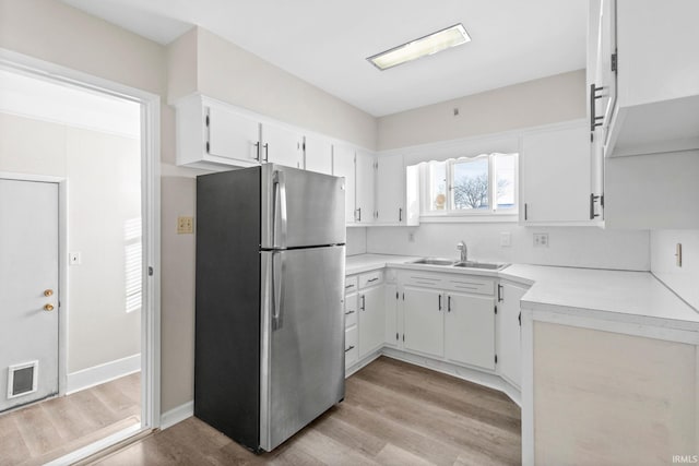 kitchen featuring light hardwood / wood-style floors, sink, white cabinetry, and stainless steel fridge