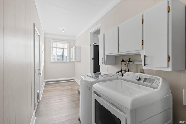 laundry area with washing machine and dryer, cabinets, wood walls, ornamental molding, and light hardwood / wood-style flooring