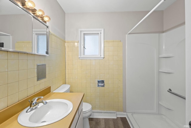 bathroom featuring tile walls, hardwood / wood-style flooring, toilet, walk in shower, and vanity