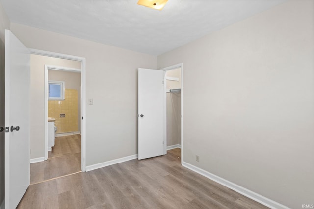 unfurnished bedroom with a closet, a walk in closet, and light wood-type flooring