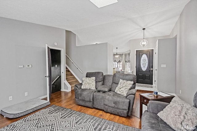 living room featuring lofted ceiling, hardwood / wood-style flooring, and an inviting chandelier