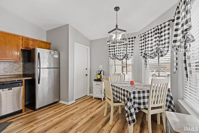 dining space featuring vaulted ceiling, an inviting chandelier, and light hardwood / wood-style floors