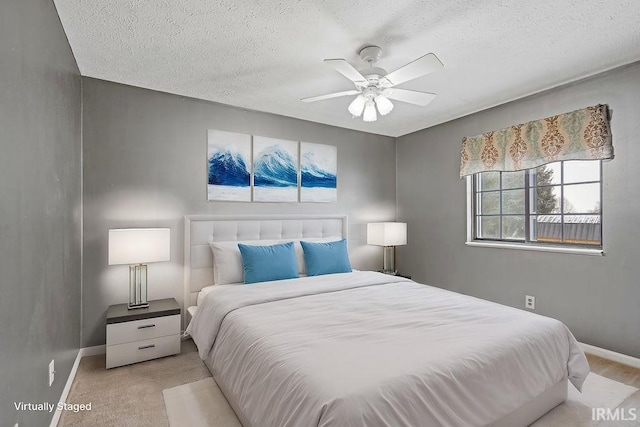 bedroom featuring a textured ceiling, light colored carpet, and ceiling fan