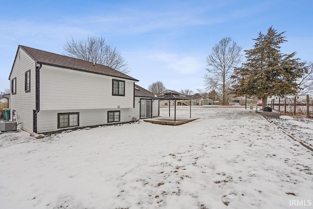 snow covered back of property featuring central AC unit and a gazebo