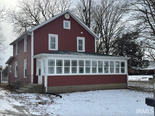 snow covered property featuring a sunroom