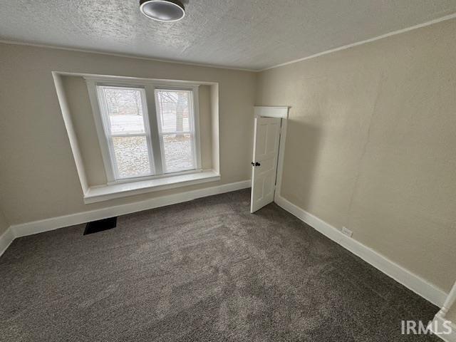 spare room with dark carpet and a textured ceiling