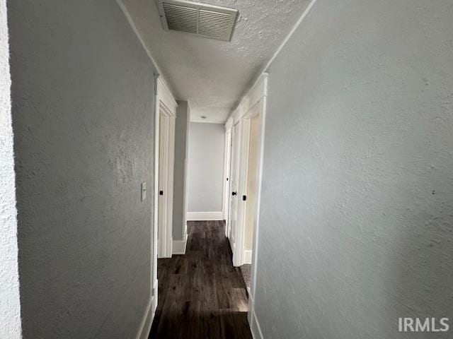 corridor featuring dark wood-type flooring and a textured ceiling