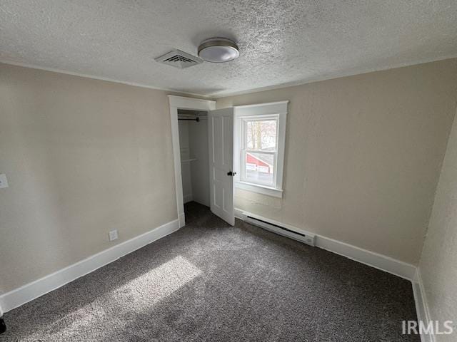 unfurnished bedroom featuring carpet floors, baseboard heating, a textured ceiling, and a closet