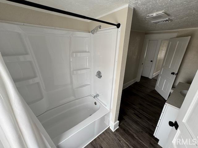 bathroom featuring hardwood / wood-style flooring, shower / tub combo, and a textured ceiling