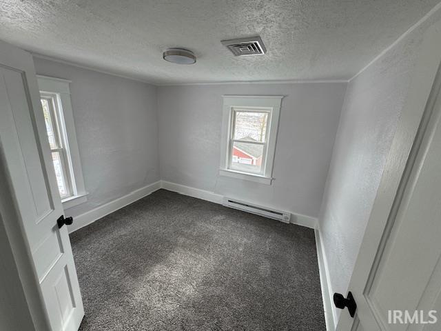 carpeted spare room featuring a textured ceiling and a baseboard heating unit