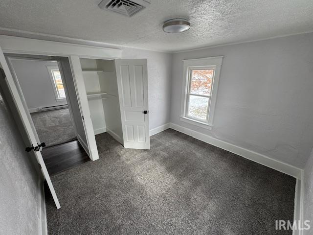 unfurnished bedroom featuring dark carpet, a closet, and a textured ceiling