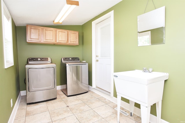 washroom with sink, light tile patterned floors, cabinets, and independent washer and dryer