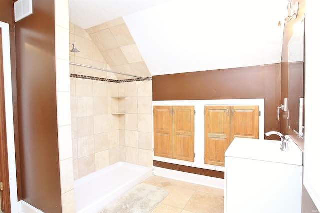 bathroom featuring tiled shower, tile patterned flooring, vaulted ceiling, and vanity