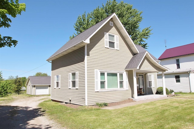 view of front of property featuring a garage, a front lawn, and an outdoor structure