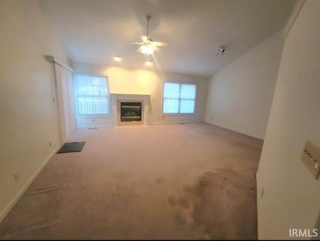 unfurnished living room featuring light carpet, a healthy amount of sunlight, and ceiling fan