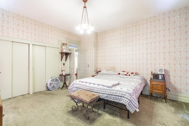 bedroom featuring an inviting chandelier, carpet flooring, and two closets