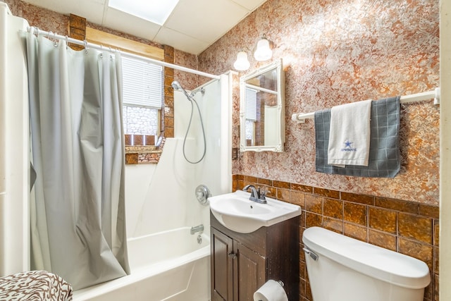 full bathroom with shower / bathtub combination with curtain, vanity, tile walls, toilet, and a drop ceiling