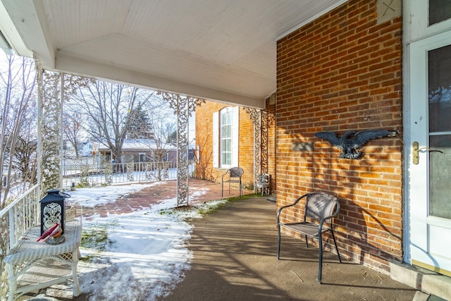 snow covered patio featuring covered porch