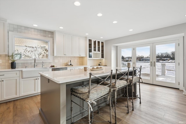 kitchen with a center island, a kitchen bar, sink, white cabinets, and light hardwood / wood-style flooring