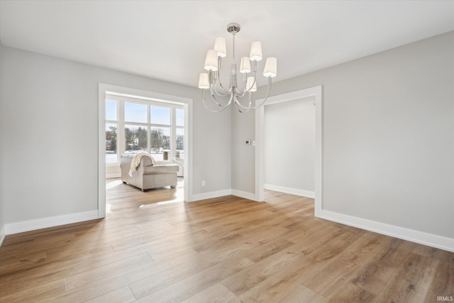 spare room featuring an inviting chandelier and light hardwood / wood-style floors