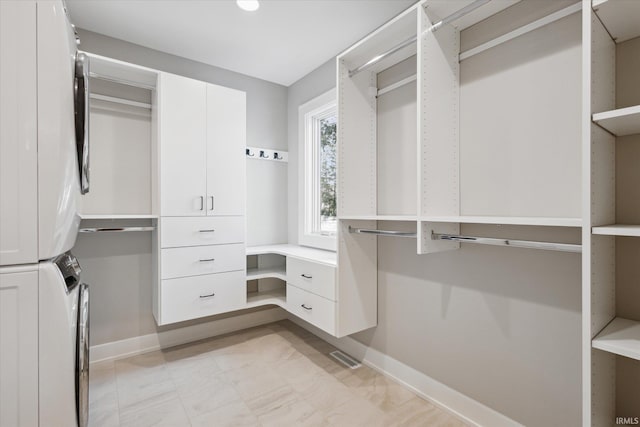 spacious closet with stacked washer / dryer and built in desk