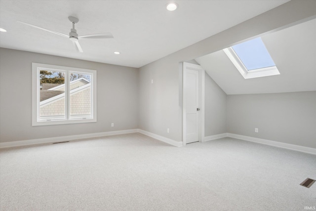 bonus room featuring light colored carpet, vaulted ceiling with skylight, and ceiling fan