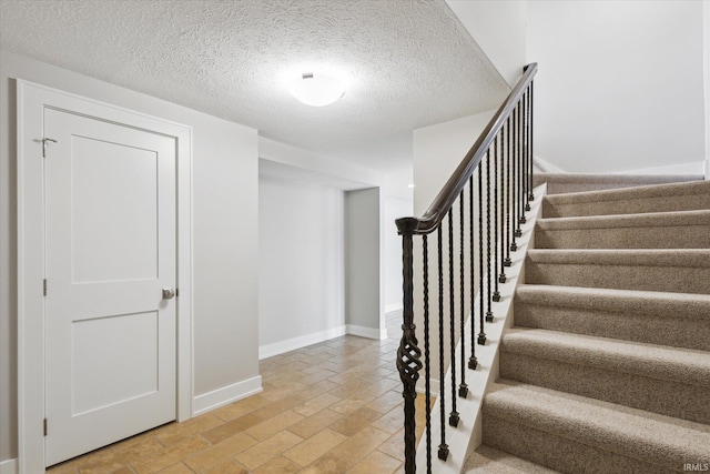 stairs featuring a textured ceiling