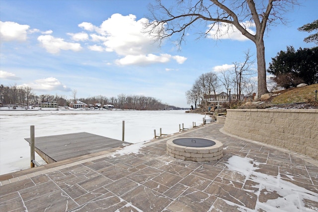 snow covered patio with an outdoor fire pit and a dock