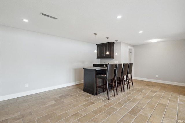 kitchen featuring dark brown cabinets, kitchen peninsula, a kitchen bar, and sink