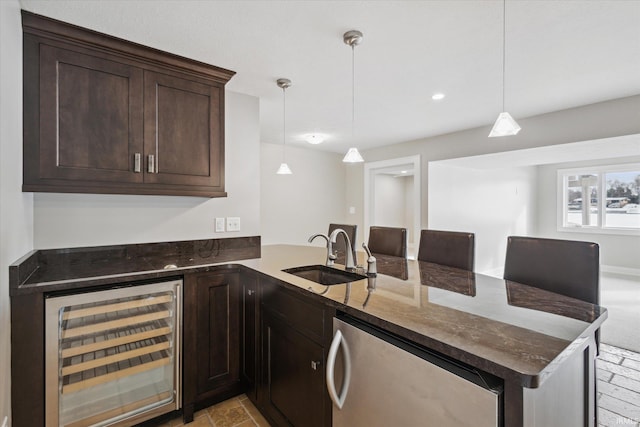 kitchen with sink, decorative light fixtures, kitchen peninsula, and beverage cooler