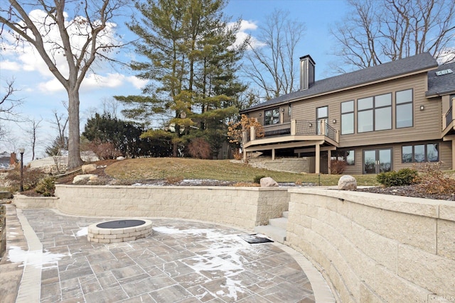 rear view of property featuring an outdoor fire pit, a wooden deck, and a patio area