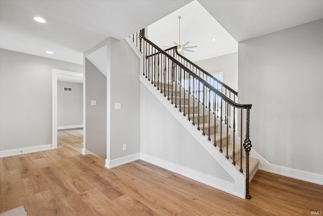 stairs featuring ceiling fan and wood-type flooring